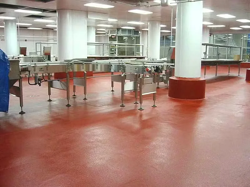 Food production area with conveyor systems and red industrial epoxy flooring designed for sanitation and durability.
