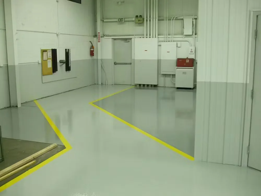 Industrial interior with light gray epoxy floor coating and bright yellow safety line striping around electrical panels and walkways.