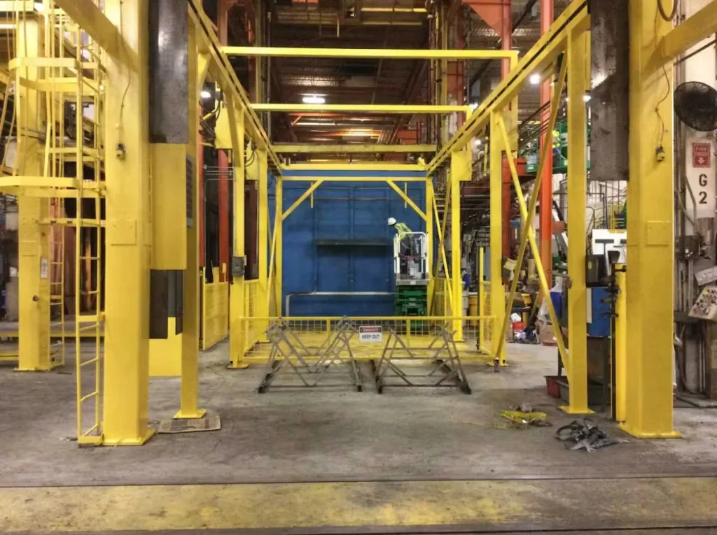 Structural steel framework painted bright yellow inside an industrial facility, highlighting safety markings and protective coatings during a commercial painting project.