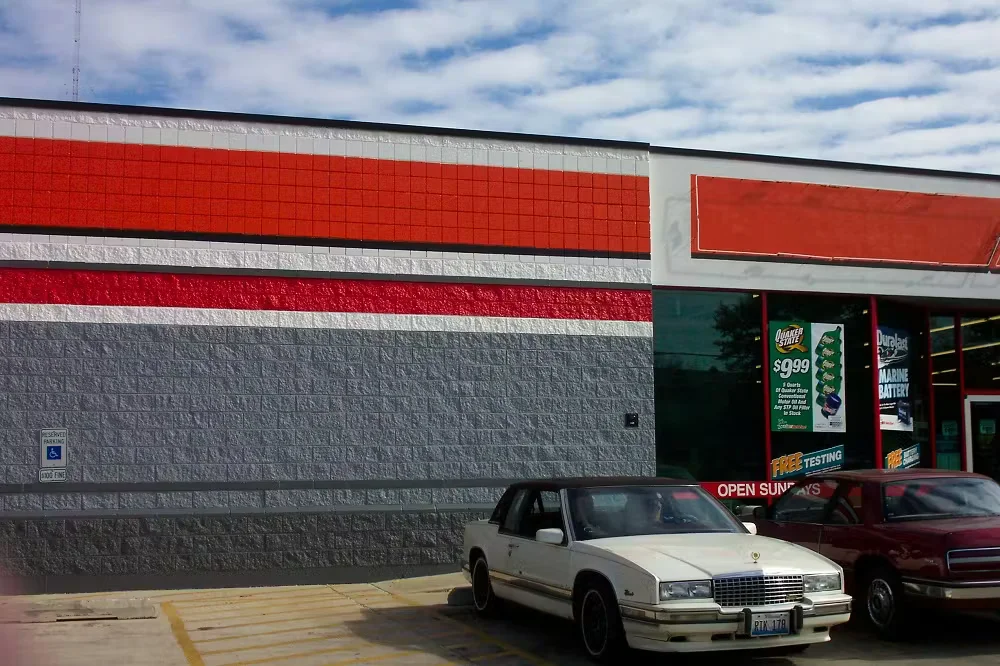 Freshly painted commercial retail storefront with red, white, and gray exterior facade, storefront windows, and customer parking spaces in front.