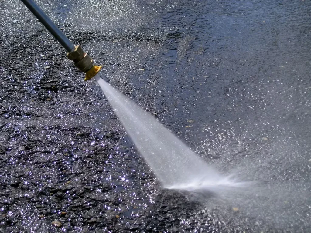 High-pressure water spray cleaning an asphalt or concrete surface as part of commercial and industrial maintenance programs.