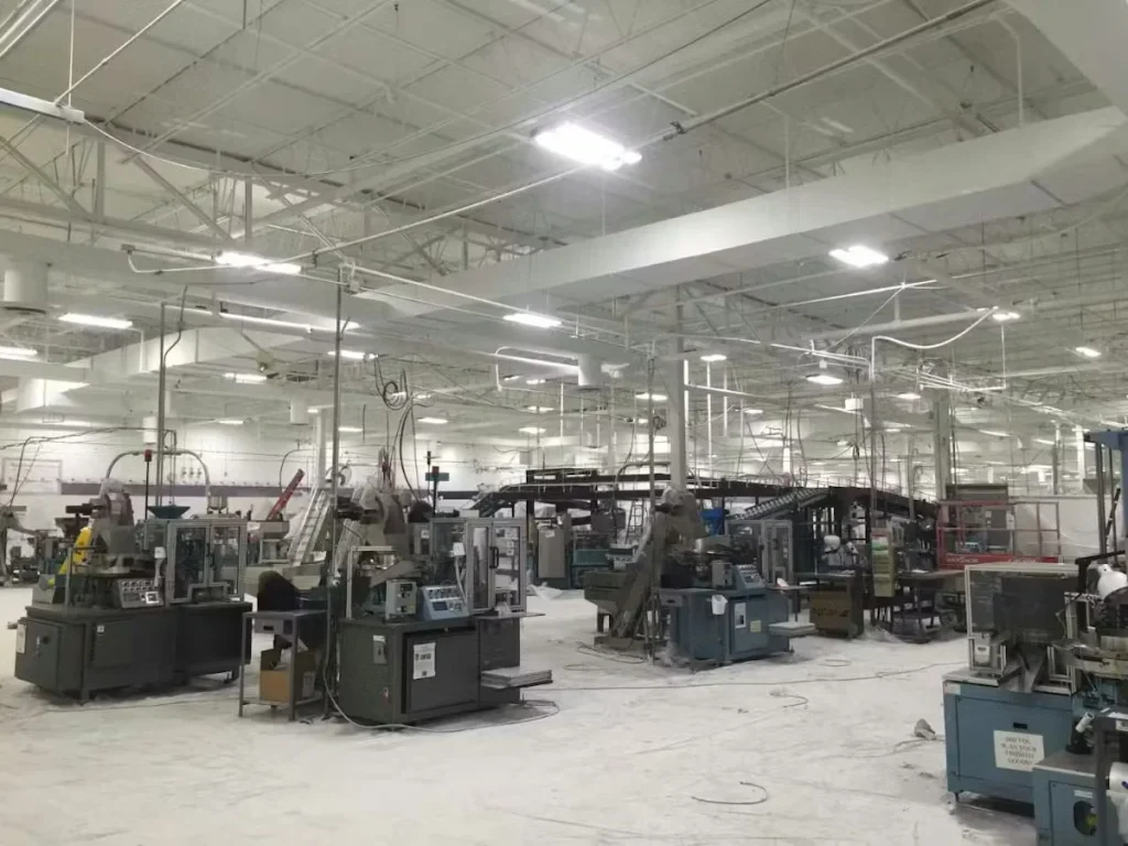 Large manufacturing facility interior with machinery, equipment lines, and freshly painted white ceiling and structural beams.
