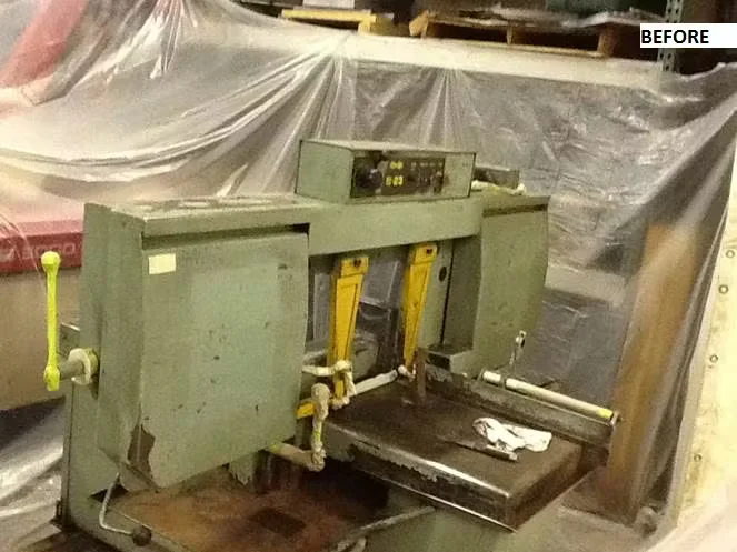 Before image of an industrial machine with worn green paint and surface rust, surrounded by protective plastic sheeting in a manufacturing facility prior to electrostatic painting.