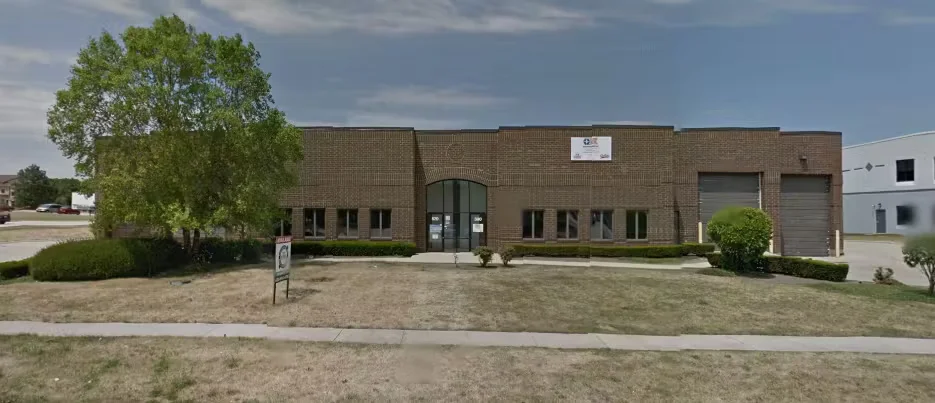 Exterior view of Painters USA Inc. headquarters building prior to relocating, featuring a brick commercial facility with front entrance and parking area.