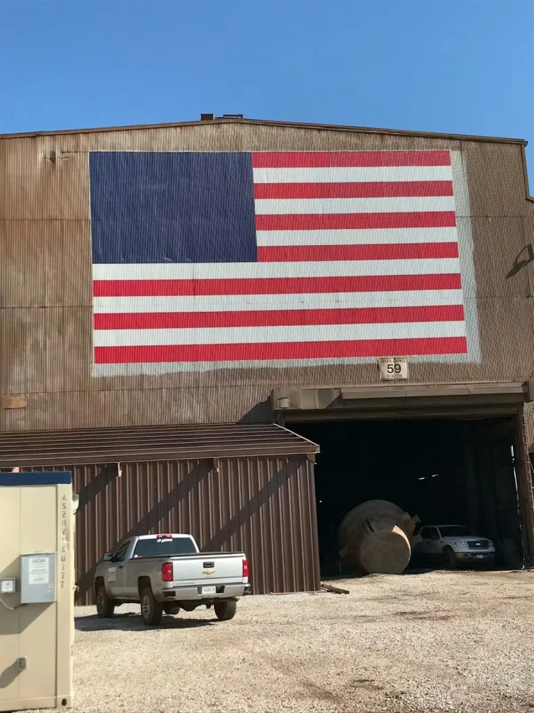 Large American flag mural painted on the exterior wall of an industrial building.