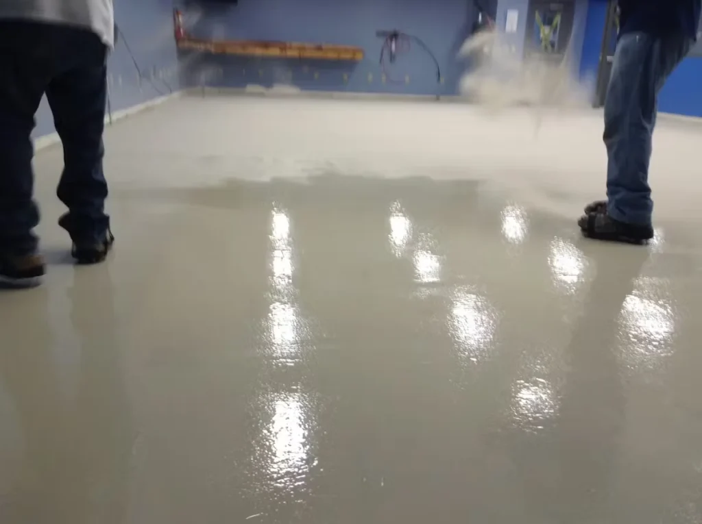 Workers installing an anti-slip epoxy floor system in an industrial facility, showing freshly applied glossy coating for improved safety and durability in Illinois.