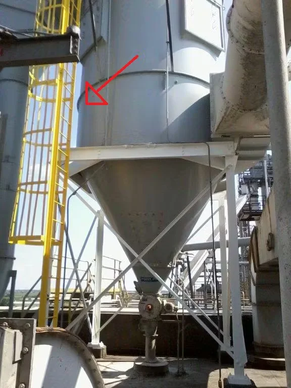 Industrial storage silo with visible rust areas highlighted by a red arrow, showing a section prepared for rust encapsulation and corrosion control.