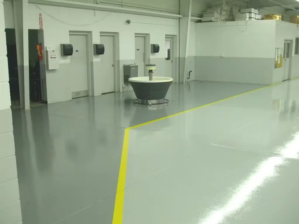 ESD epoxy floor system installed in an industrial facility with gray flooring and yellow safety line striping.