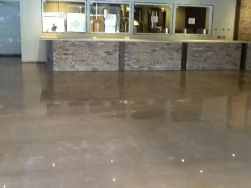 Polished concrete floor in a lobby area reflecting lights, with a long stone-faced counter and interior windows along the back wall.