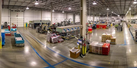 EV and battery facility flooring—wide industrial production space with smooth polished floors, machinery, and storage areas.