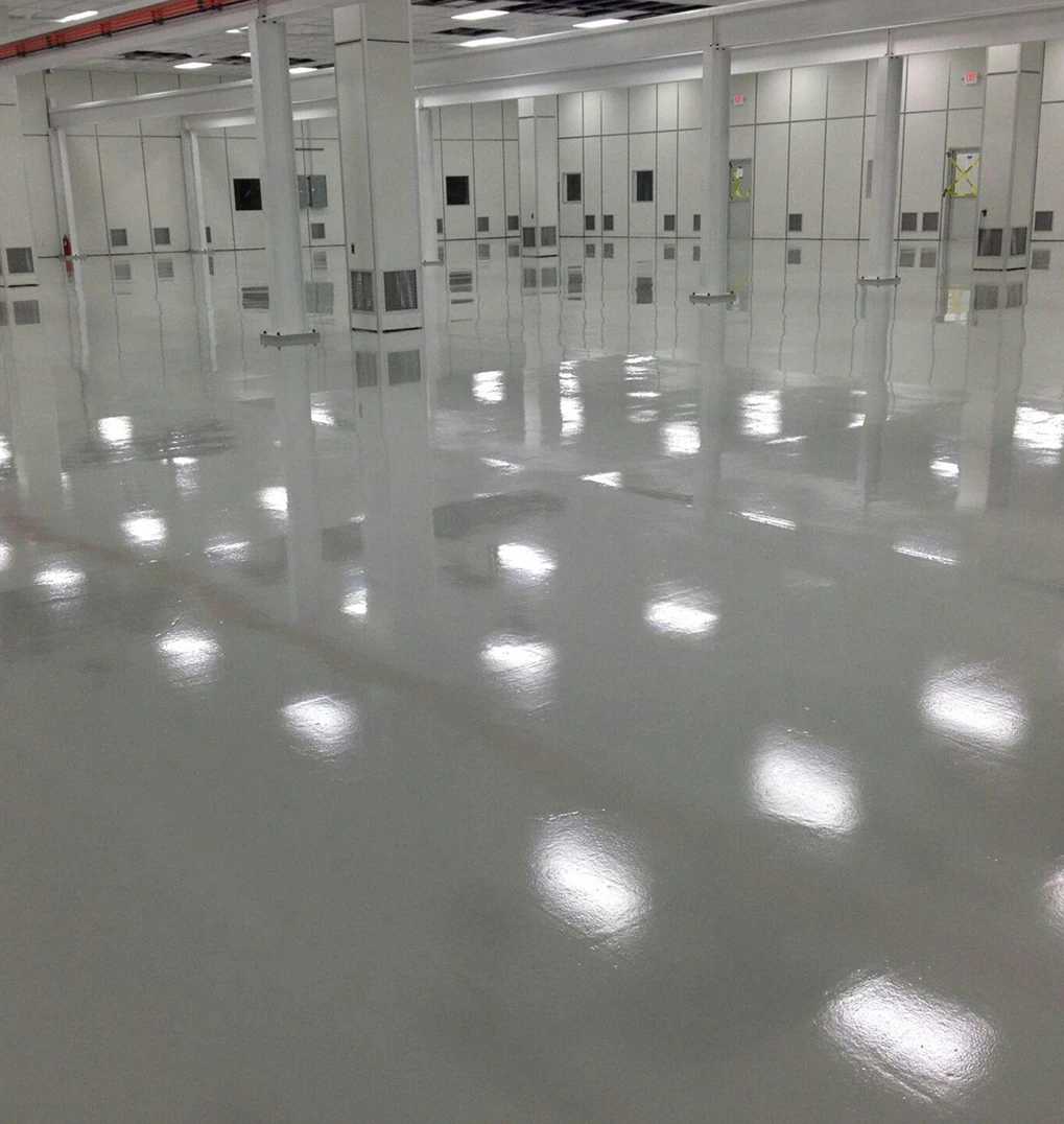 A pristine white facility interior with reflective, high-quality epoxy flooring, clean walls, and evenly spaced support columns.