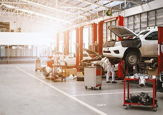 Automotive industry repair shop with cars on hydraulic lifts and technicians working.