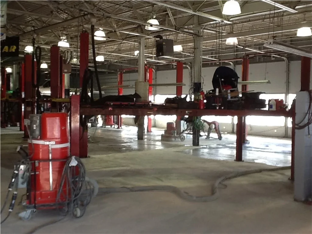 Auto repair shop with multiple vehicles parked inside, featuring a bright epoxy-coated floor for durability and cleanliness.