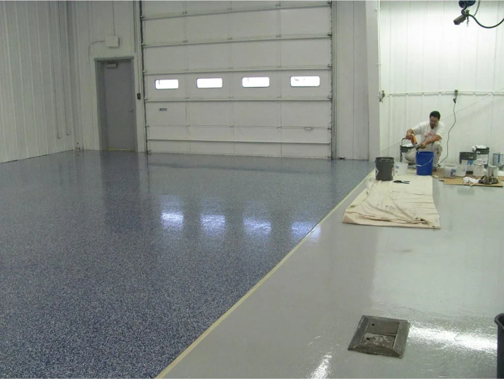 Red pickup truck parked on a finished epoxy flake garage floor inside a bright automotive service area.