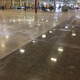 Large industrial floor with polished concrete, showing a glossy finish that reflects overhead lighting.