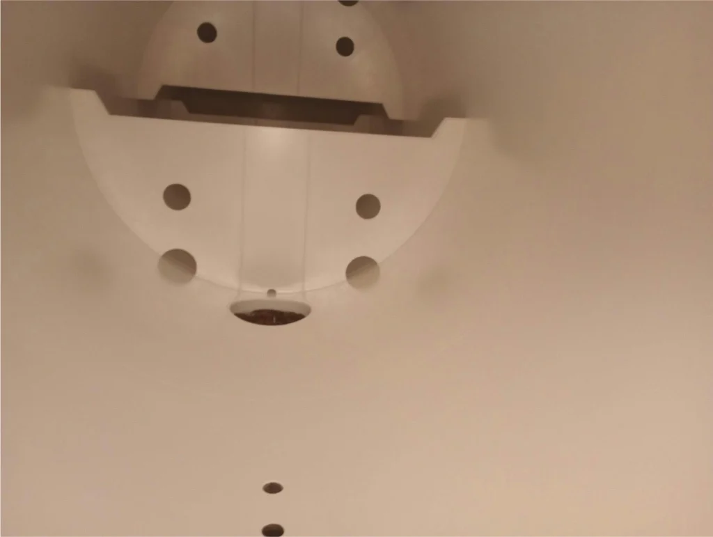 Freshly coated white interior of a storage tank with circular ports and a central drain, viewed from inside.