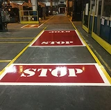 Industrial facility floor with bright yellow safety lines and large red stop zones clearly marked for traffic and pedestrian guidance.