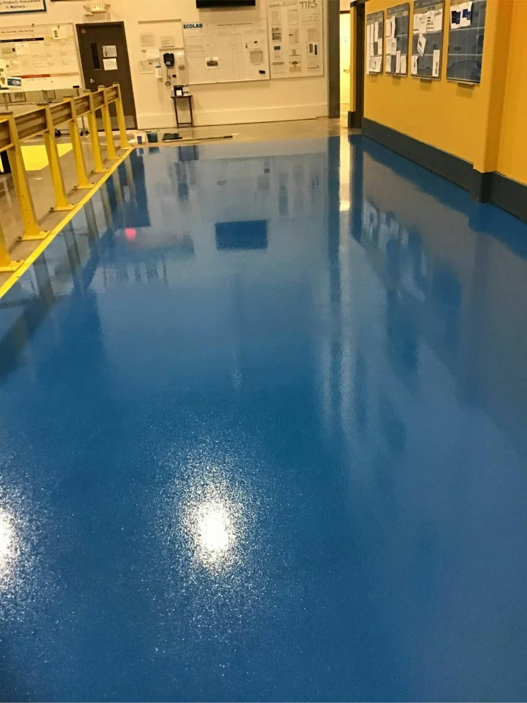 Hallway after epoxy: bright blue, high-gloss floor with yellow guardrails and bulletin boards.