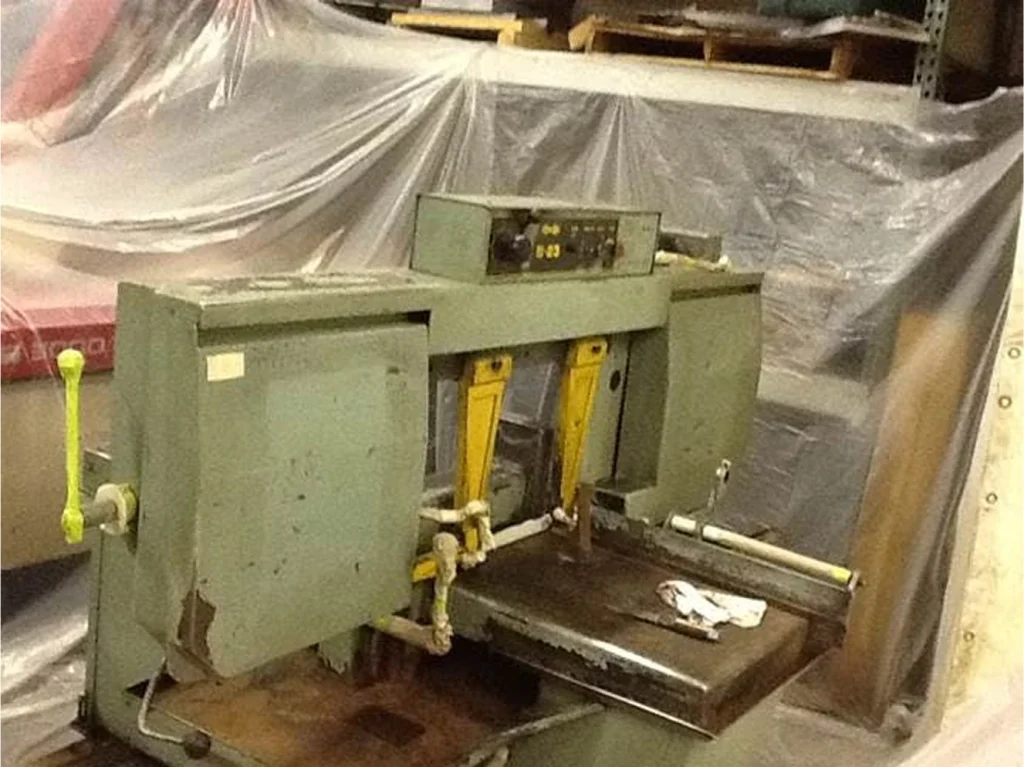 Metal bandsaw before cleaning, with chipped green paint, rusted surfaces, and worn guards in a shop area.
