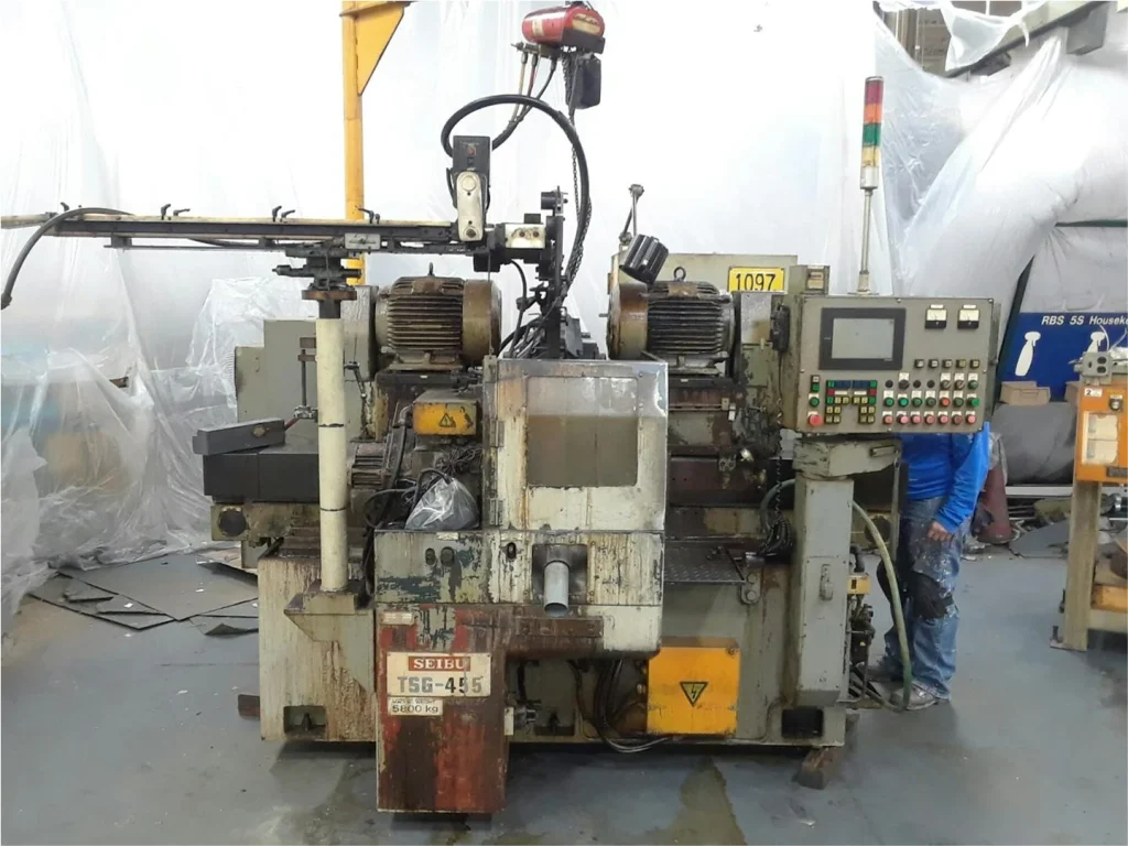 Same machine before restoration, covered in oil stains and rust with peeling paint and exposed components.