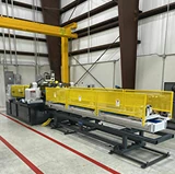 Industrial machinery with yellow safety guards being freshly painted inside a warehouse facility.