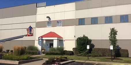 Tilt-up precast painting—worker on a lift painting the exterior wall of a large commercial building.