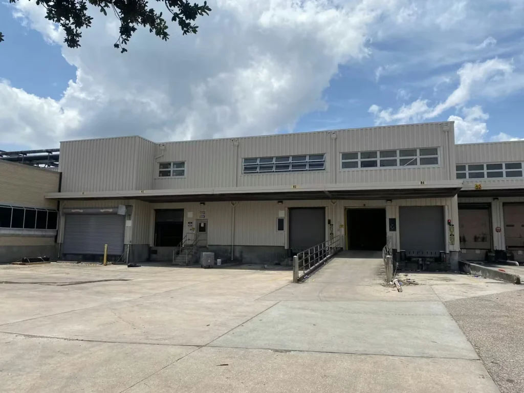 Loading dock entrance with a metal canopy and stairs, viewed from below with clear blue sky overhead.