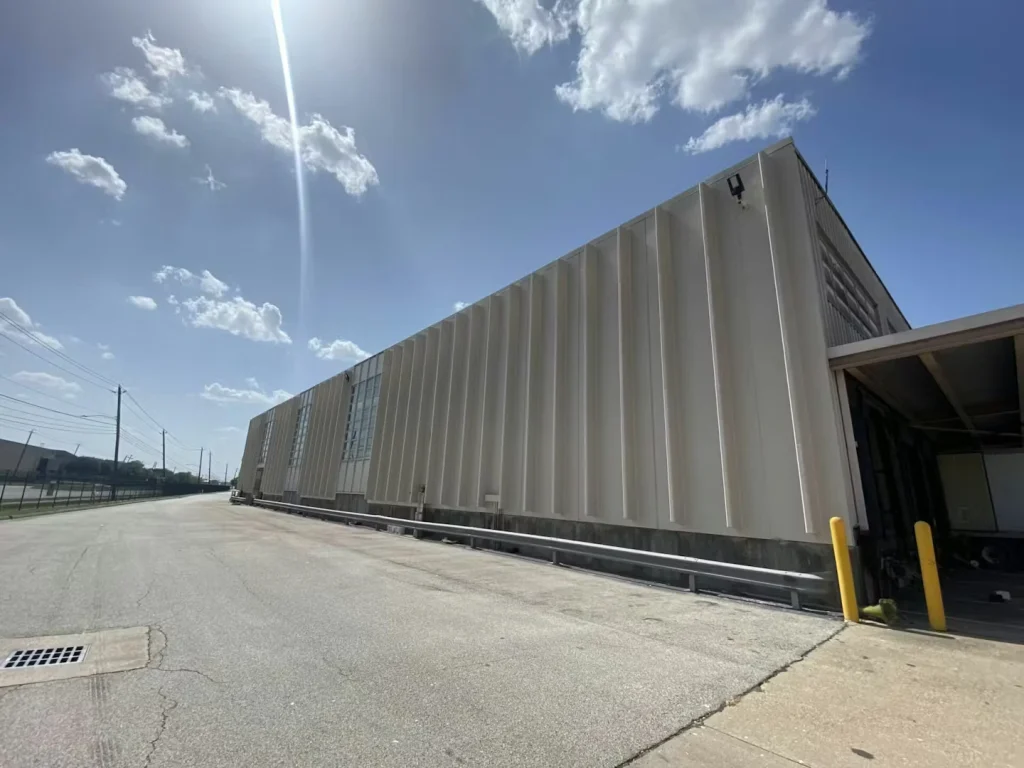 Wide view of a warehouse yard showing the loading dock area and open paved space in front of the building.