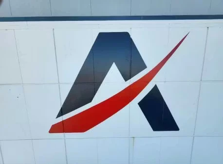 Close-up of a clean, sharply painted stylized “A” logo with a red swoosh on a white panel wall.