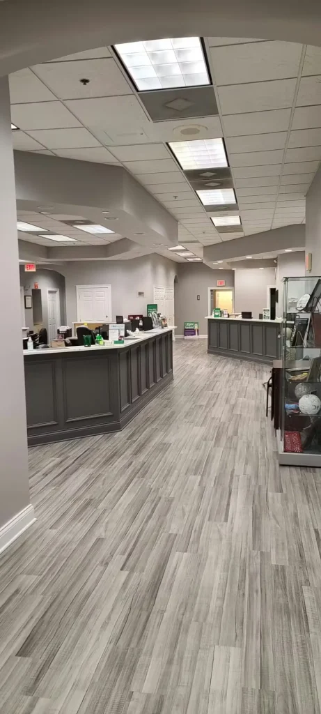 Completed clinic reception and check-in area featuring modern flooring, gray cabinetry, and updated ceiling design.