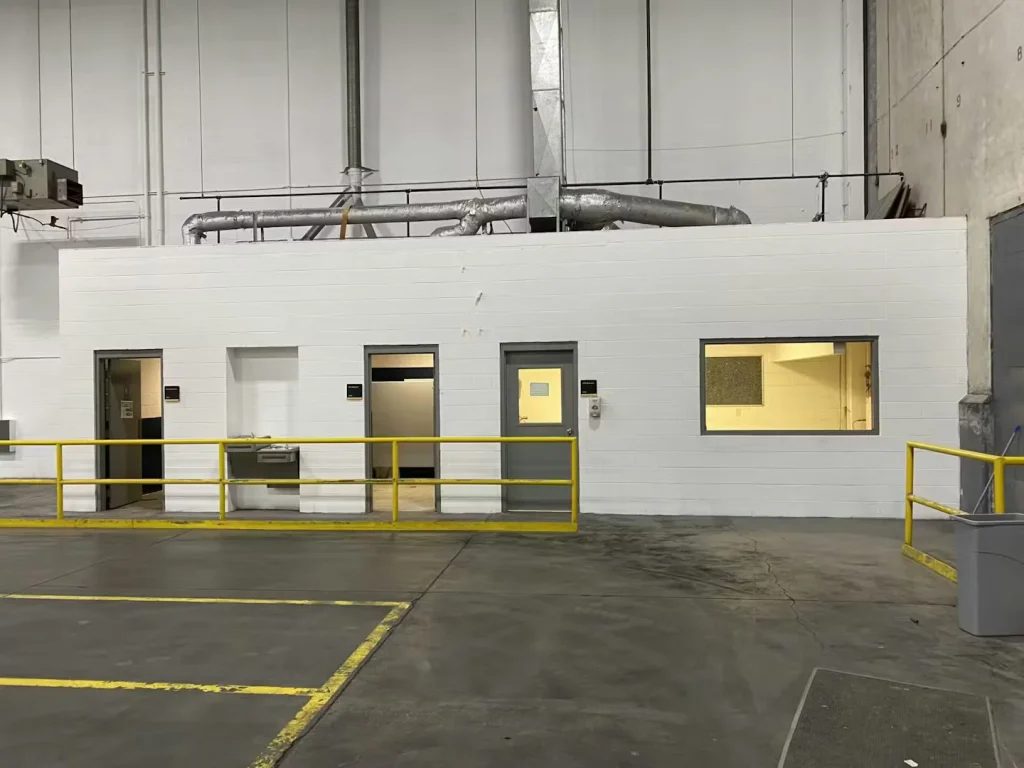 Renovated industrial office block with white painted masonry walls, gray doors, and yellow guardrails