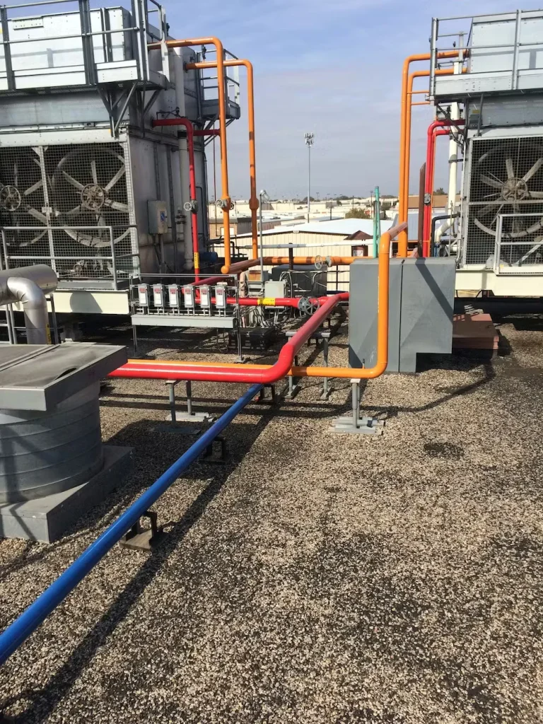 OSHA color-coded industrial piping on rooftop mechanical equipment at manufacturing facility