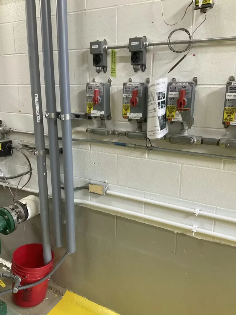 Electrical control panels and conduit on painted concrete block wall in industrial pump room