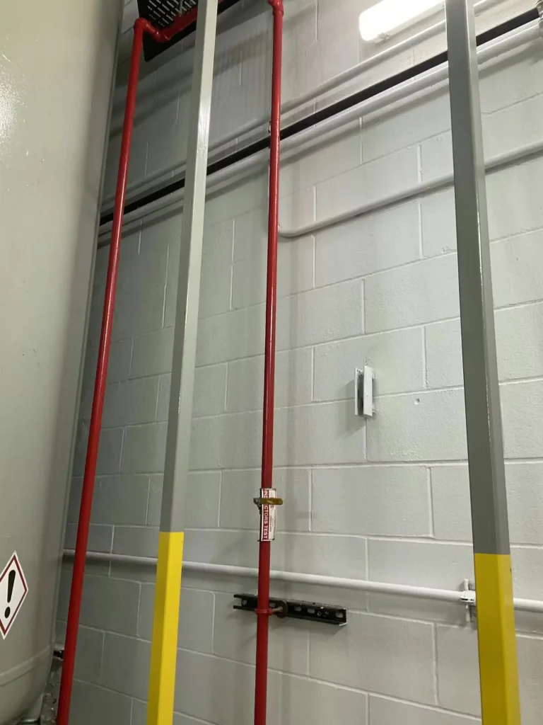 Red fire protection piping and vertical steel supports against freshly painted industrial wall