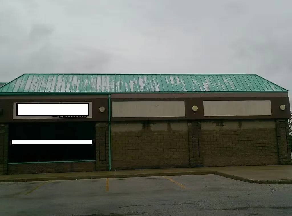 Commercial retail building with weathered green metal roof before restoration