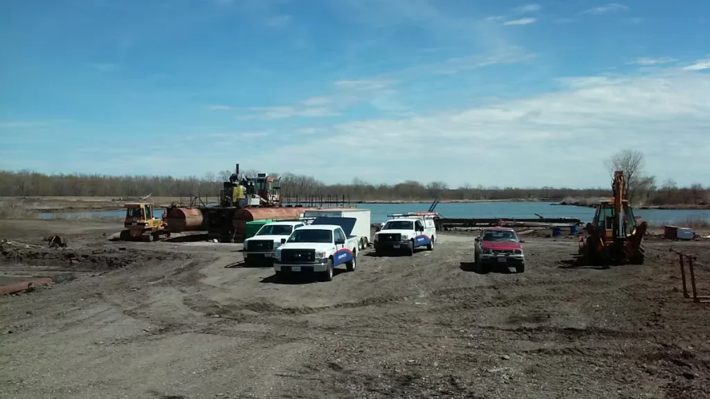 Industrial job site with service trucks and heavy equipment near waterfront