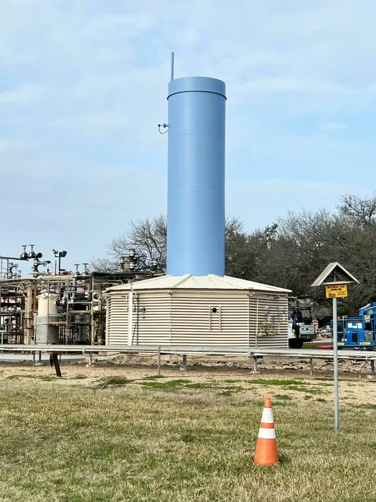 Refurbished blue industrial stack adjacent to processing equipment and gravel work area