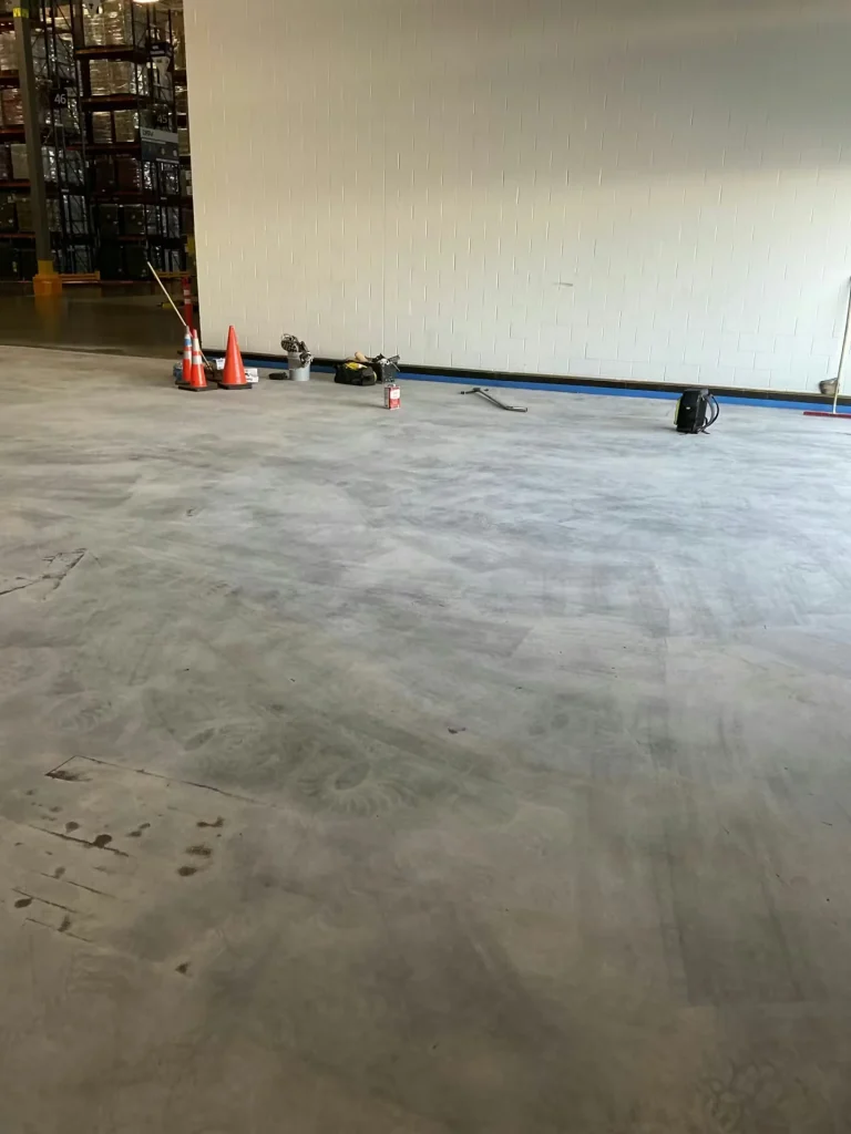 Warehouse interior with concrete floor preparation area and tools staged along the wall