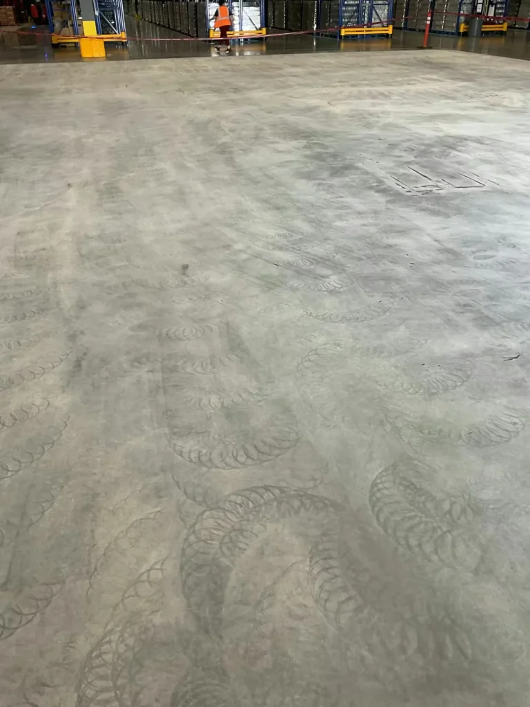 Prepared concrete warehouse floor with visible grinding patterns before epoxy application