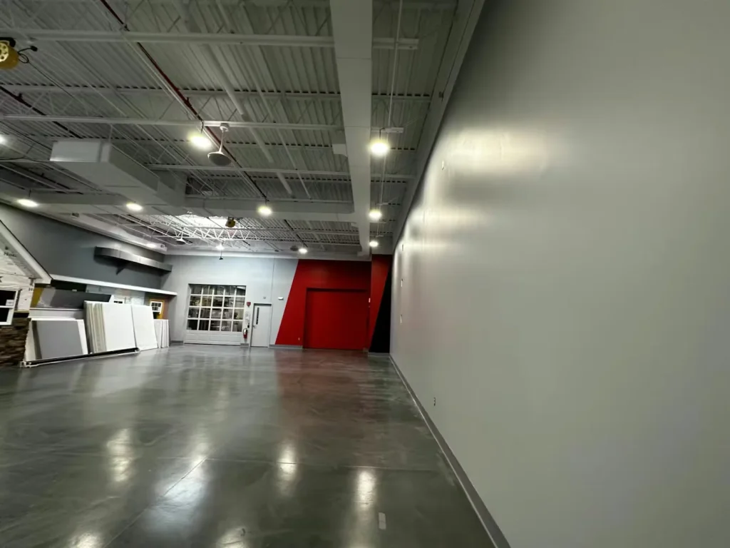 Polished concrete floor inside a modern warehouse showroom with high ceilings and bright overhead lighting