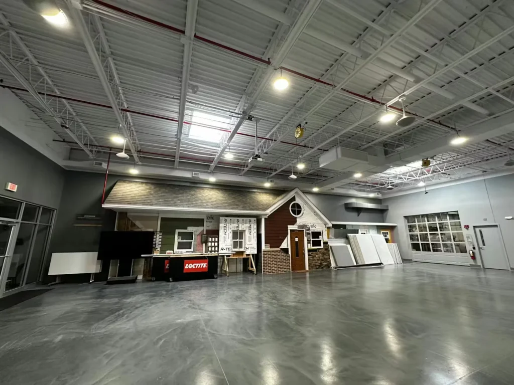 Open industrial showroom featuring polished concrete floors, display walls, and a model house façade