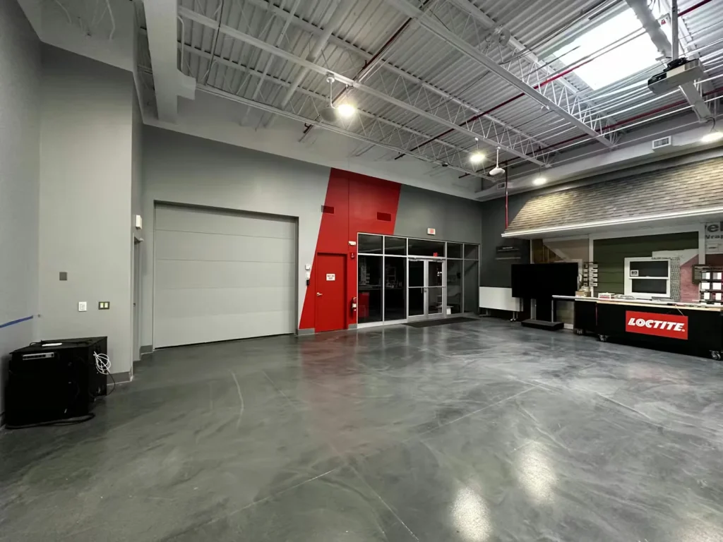 Spacious showroom area with polished concrete flooring, red accent wall, and large overhead lights